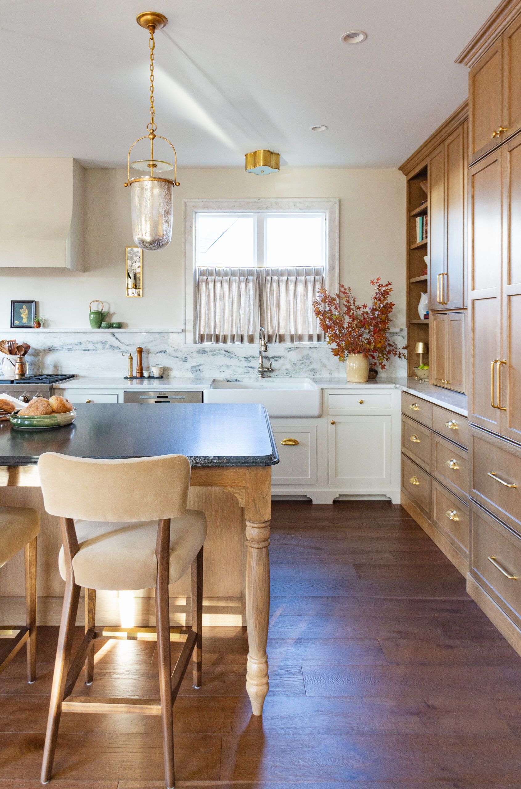 Bright kitchen with white cabinets, blue island, and a brass lantern pendant hanging from the ceiling.